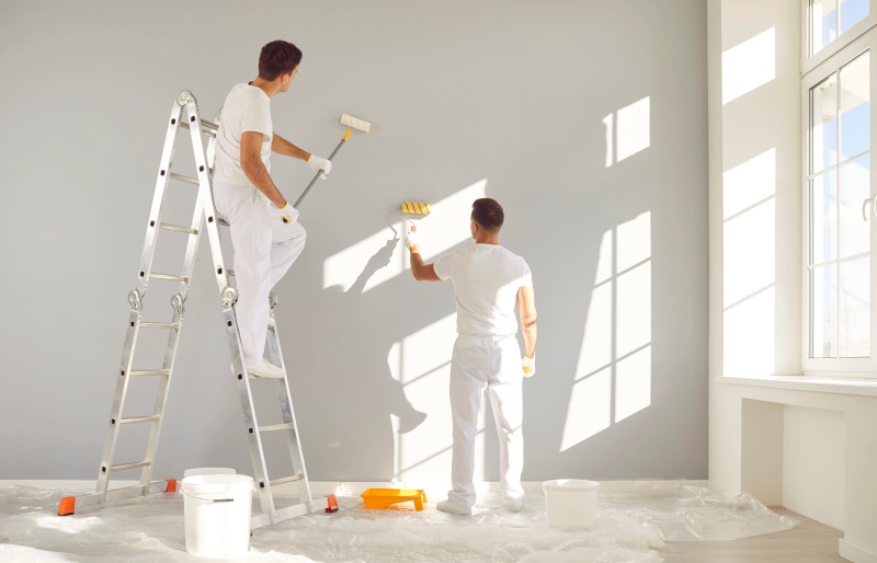 Back View Team Professional Painters White Clothes Painting Grey Wall 