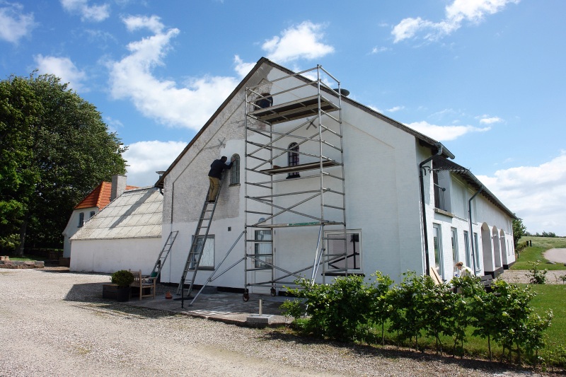 Man on scaffolds painting a house